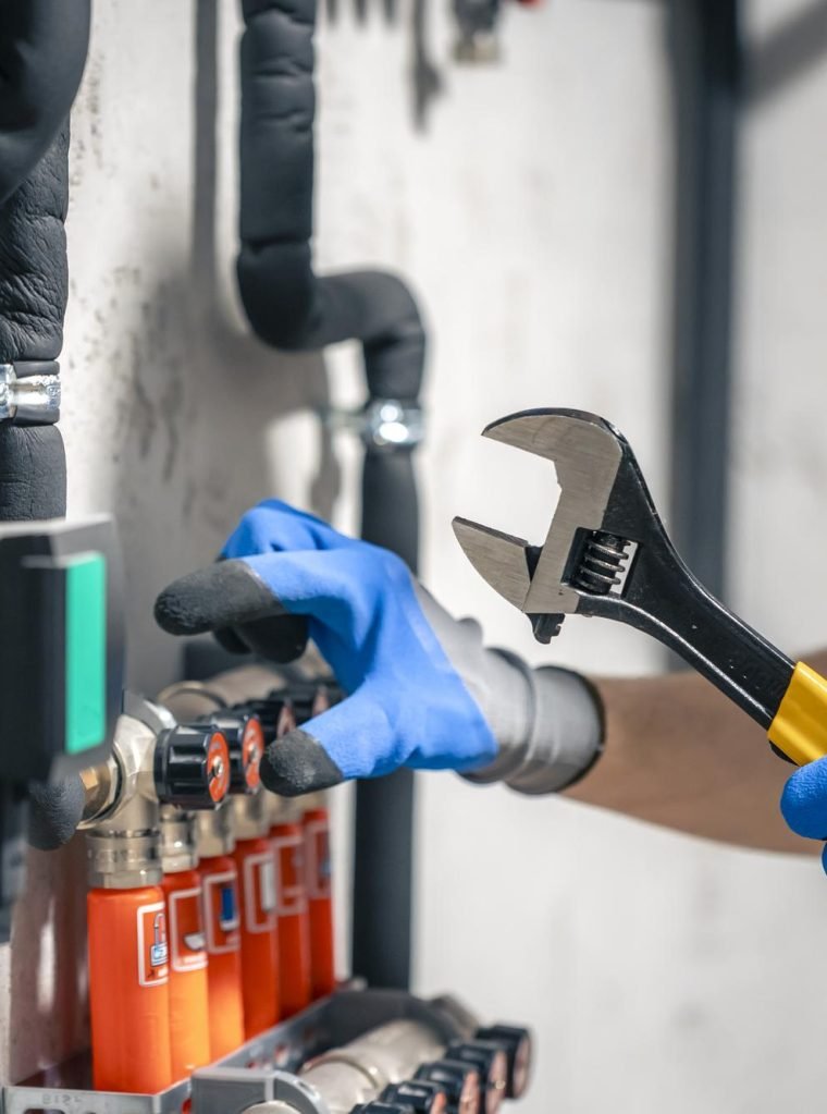 man-installs-heating-system-house-checks-pipes-with-wrench man-installs-heating-system-house-checks-pipes-with-wrench
