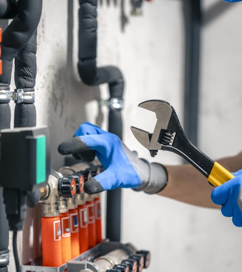 man-installs-heating-system-house-checks-pipes-with-wrench
